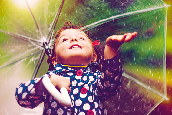 Child with umbrella catches raindrops (photo)