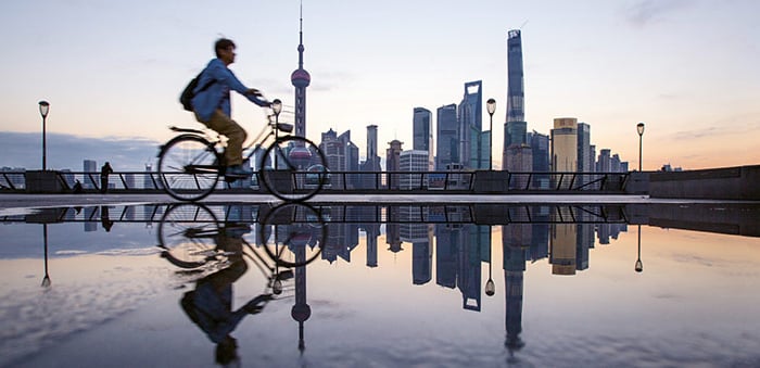 Man on bicycle in front of Shanghai skyline (photo)