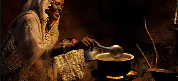 Woman using a cooking stove in a hut (photo)