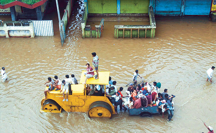 Tractor in a flooded street with people on it (photo)