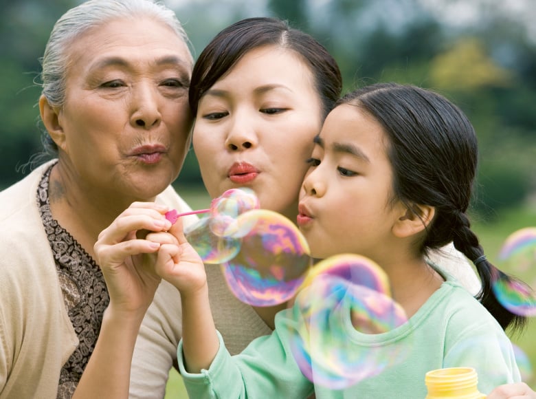 Three asian women of three different generations blowing soap bubbles together (photo)