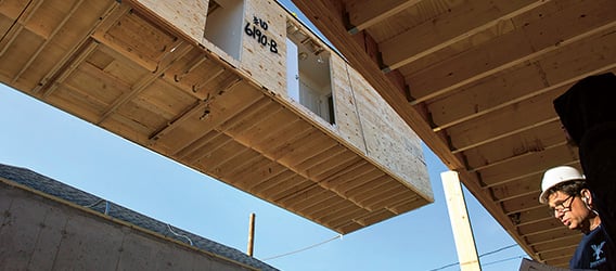 Part of a modular home unit is lifted into place at the site of a home destroyed by Hurricane Sandy. Much of the damage has been repaired but some is still visible. (photo)