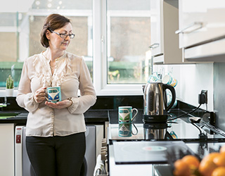 Woman standing in a kitchen holding a cup of coffee (photo)