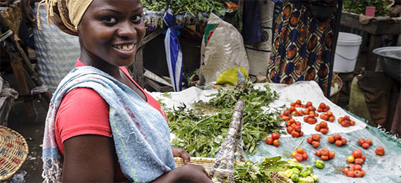 Woman handling vegetables next to a market stand (photo)