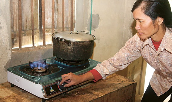 A farmer woman in Vietnam uses a cooker supplied by a newly installed biogas digester (photo)
