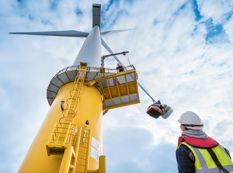 Worker looking up a wind turbine (photo)