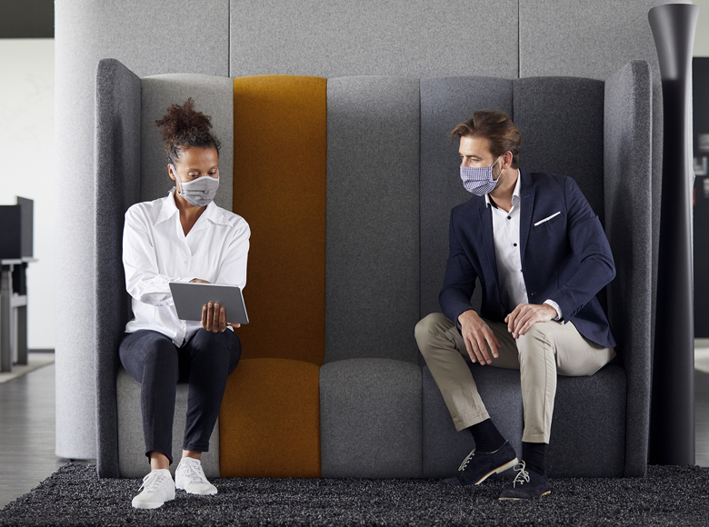 Two people sitting distant to each other and wearing masks (photo)